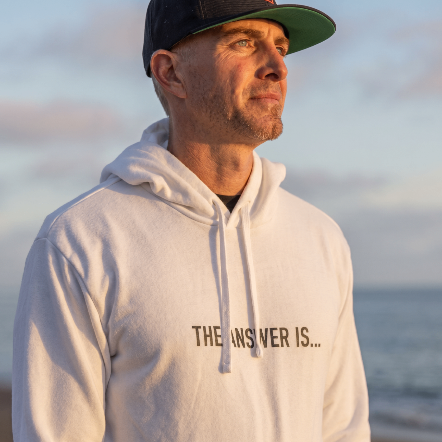 Kip Hajjar, founder of The Answer Is, at the beach at golden hour wearing THE ANSWER IS...® apparel
