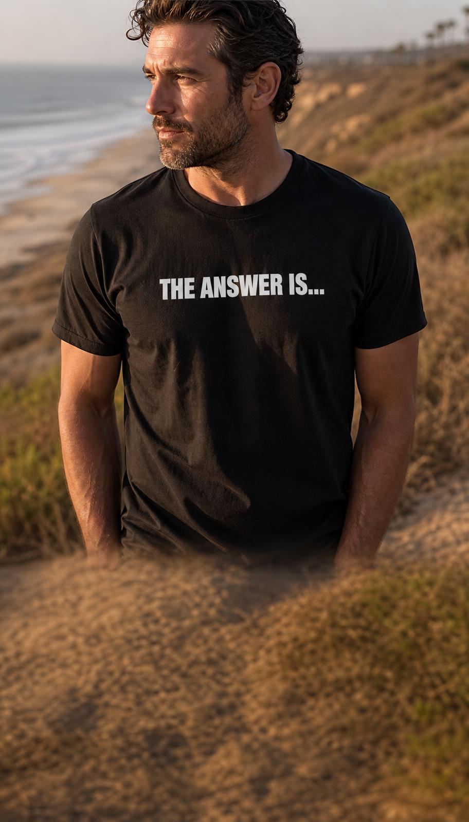 Man on a Carlsbad coastal bluff at golden hour wearing a black tee screen printed THE ANSWER IS... across the chest