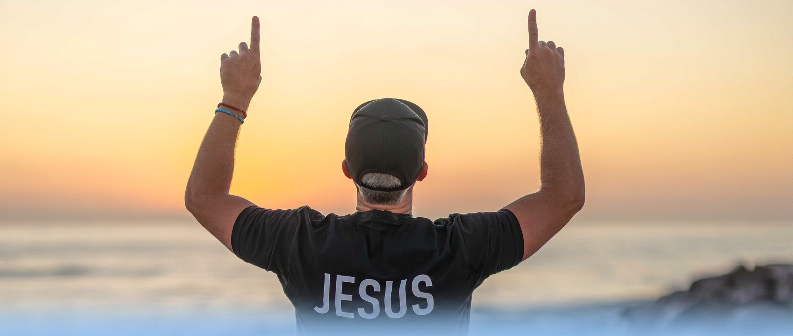 Person wearing a premium black tee at golden hour on the coast
